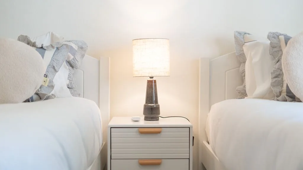 A bedroom with two beds and a bedside table between them.