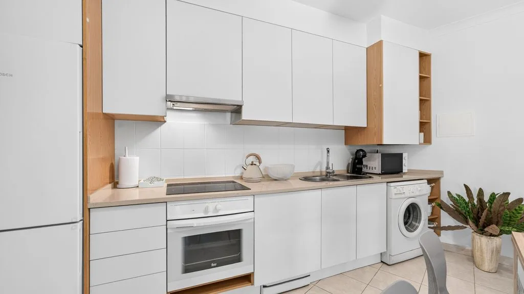 A modern kitchen with white cabinets, a countertop, and built-in appliances.