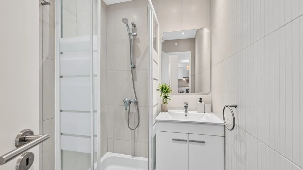 A tiled bathroom with a shower, vanity, and wall mirror.