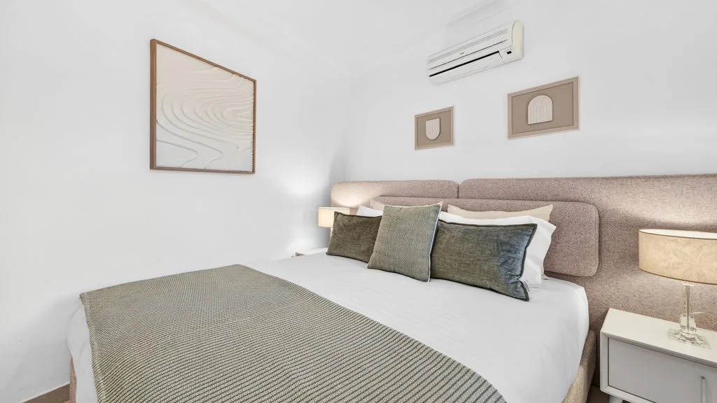 A bedroom with a neatly made bed and framed artwork on the wall.