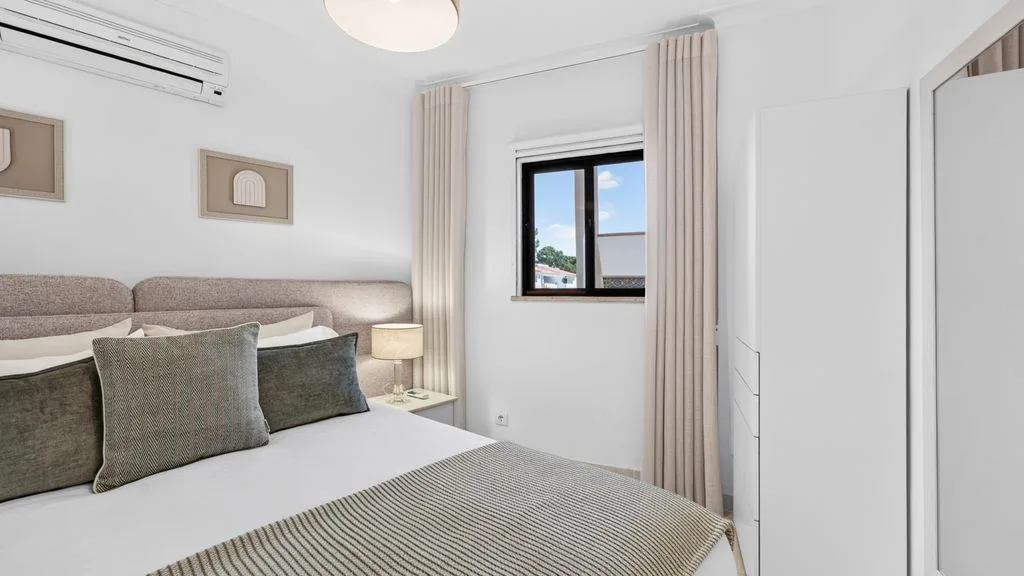 A bright bedroom with a neatly made bed and a window.