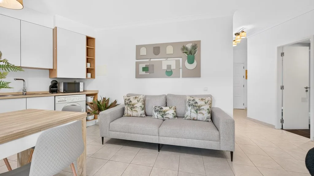 A bright open-plan living room with gray seating and a dining table.