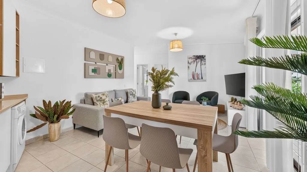 A bright dining and living area with a wooden table and seating.