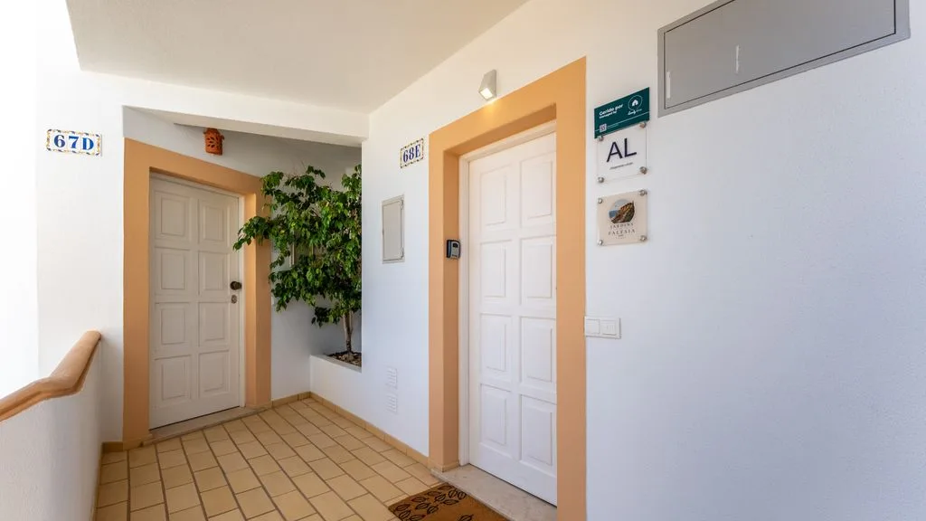 An indoor hallway with two white doors, tiled flooring, and a potted plant.