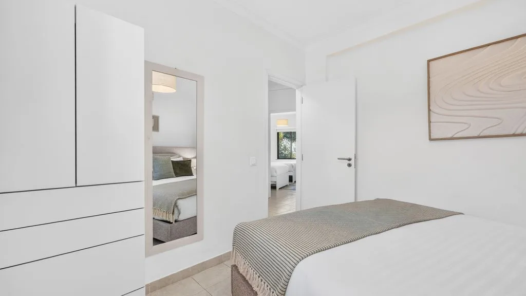 A bright bedroom with a neatly made bed and a built-in wardrobe.