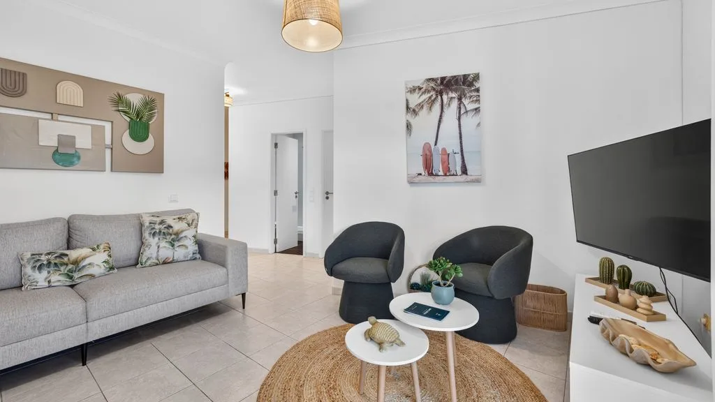 A bright living room with seating, a television, and a round rug.