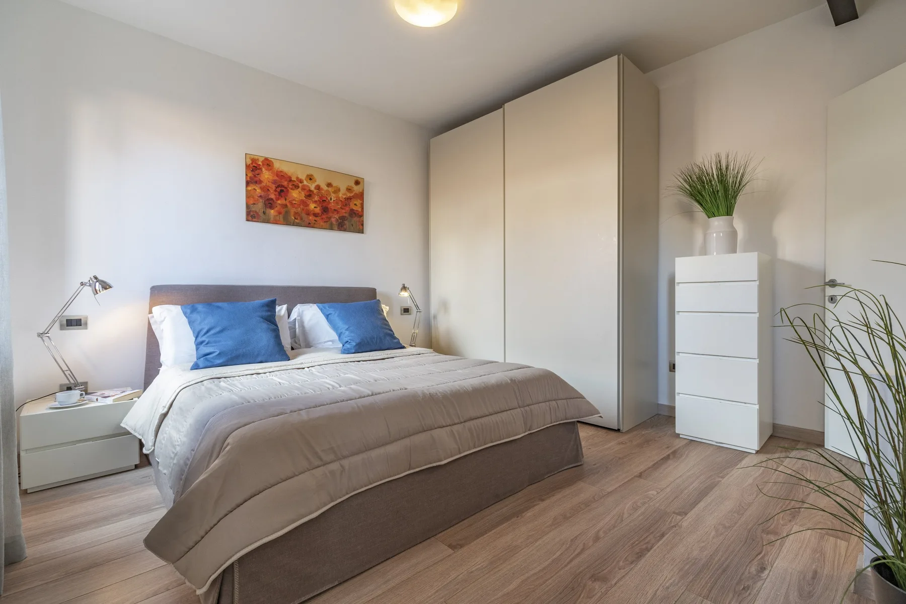 A bedroom with a neatly made bed and a tall wardrobe.