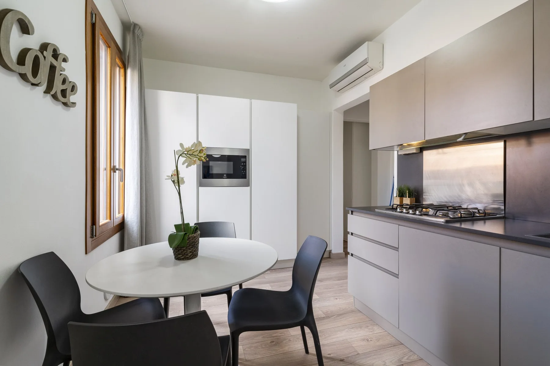 A modern kitchen and dining area with a round table and dark seating.