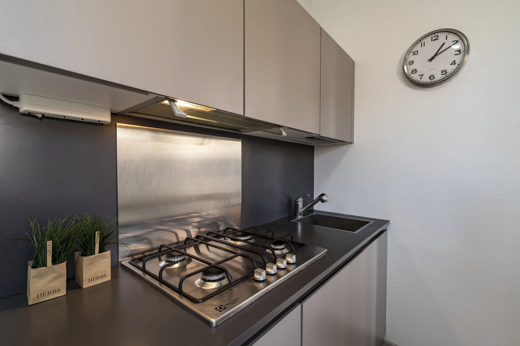 A modern kitchen with a gas cooktop and pale cabinetry.