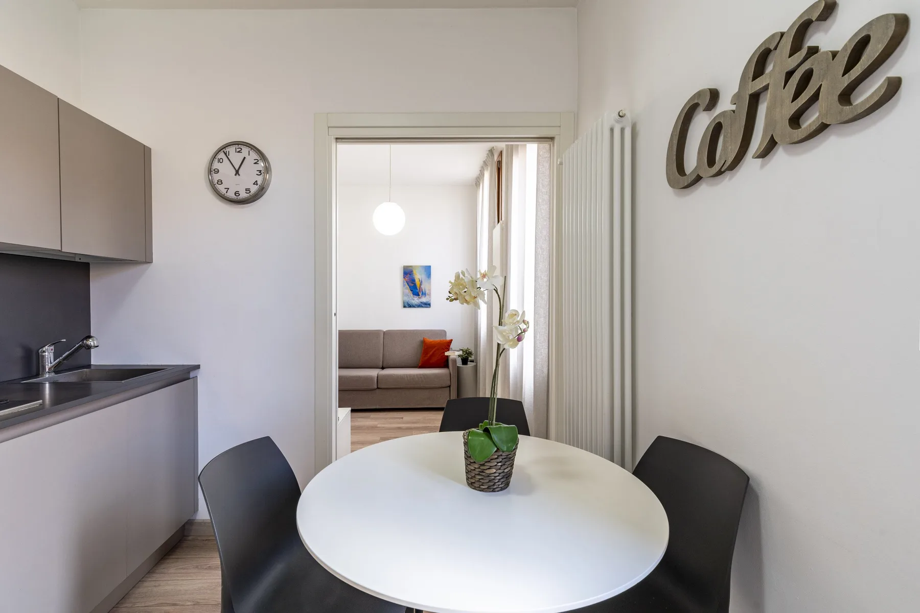 A dining area with a round table and a view into a living room.