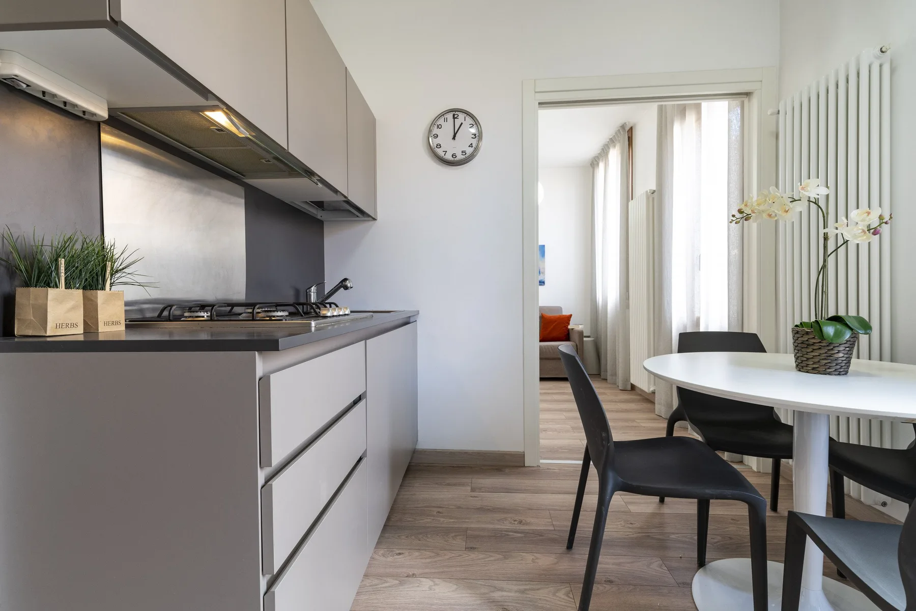 A modern kitchen opens onto a dining area with a round table and chairs.