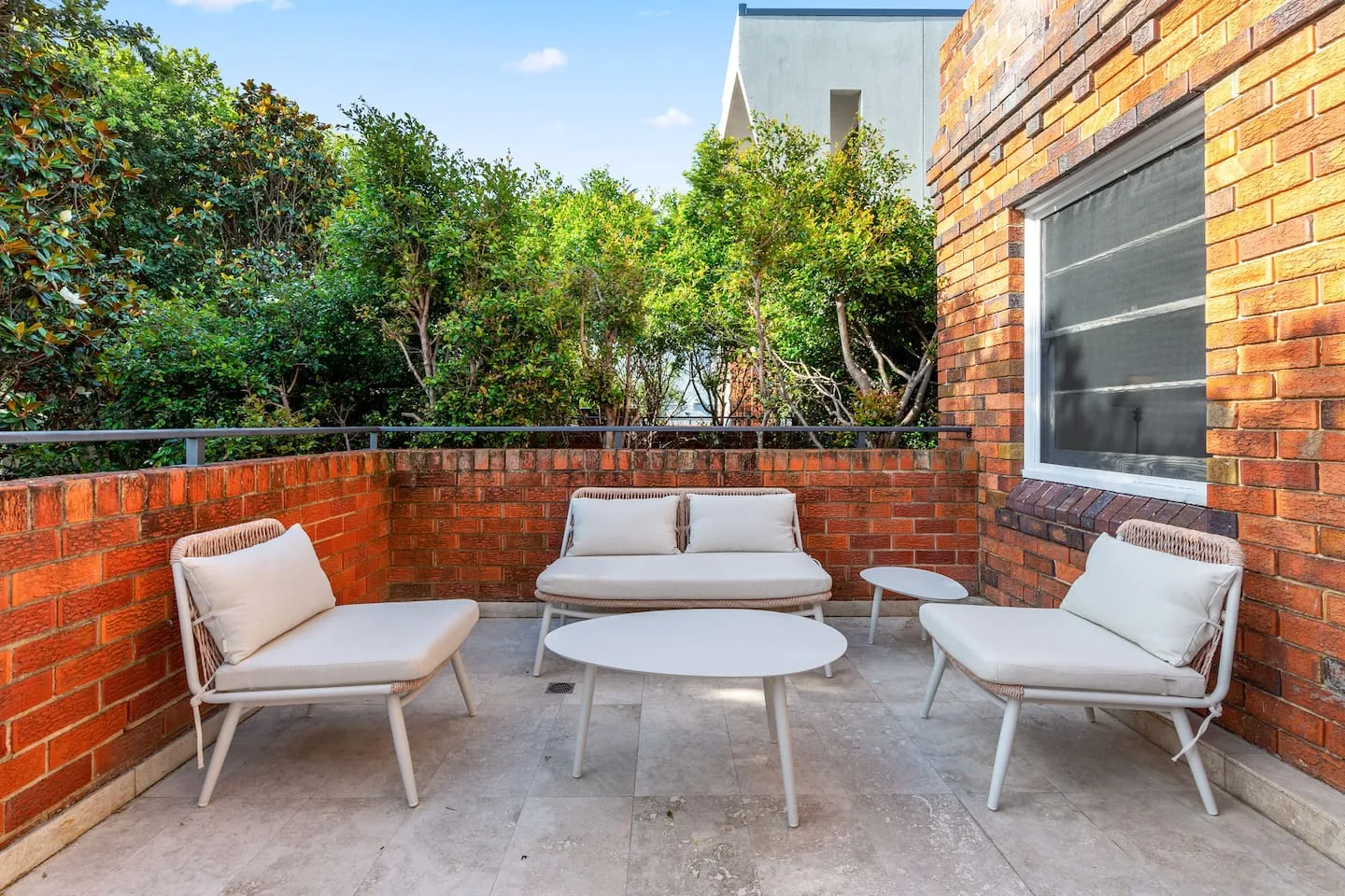 A brick-walled outdoor seating area with pale cushioned seats and a low table.