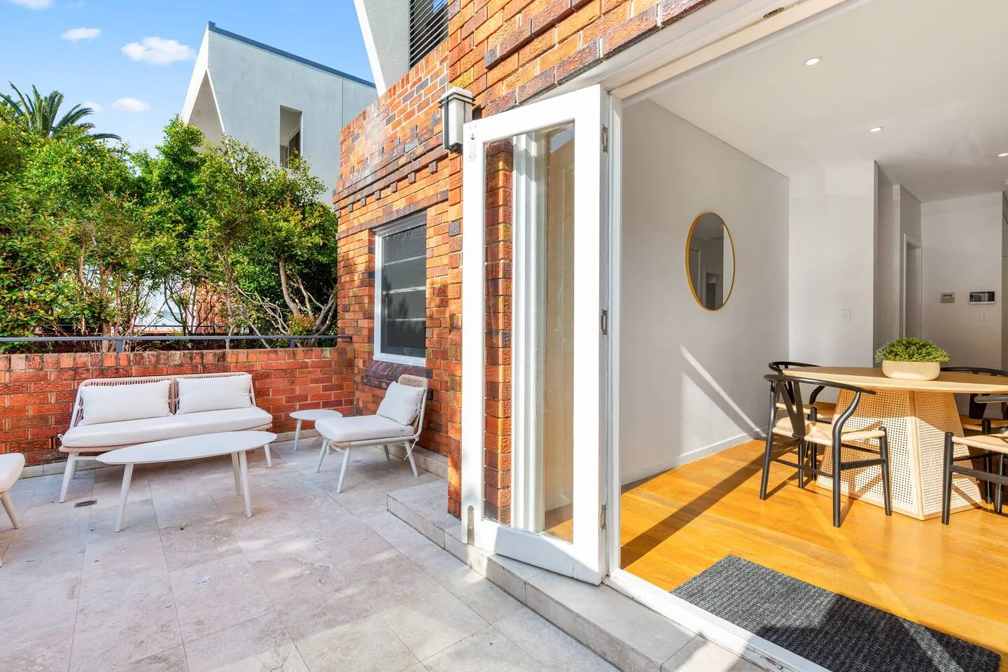 A furnished outdoor terrace beside an open doorway to a dining area.