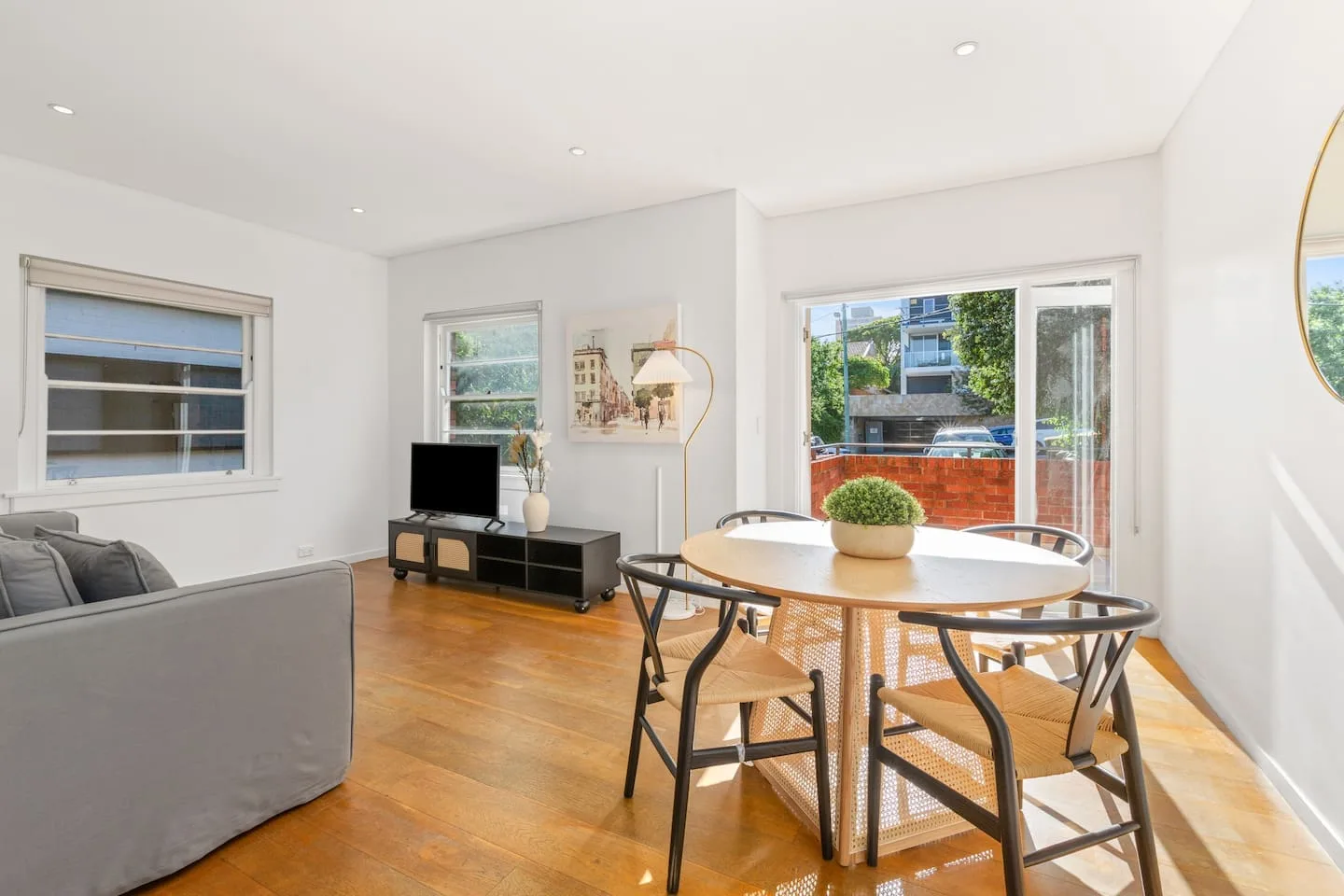 A bright dining area has a round table and chairs beside large windows.