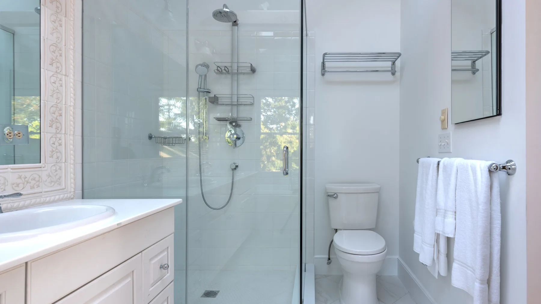 A bathroom with a glass shower, toilet, and vanity.