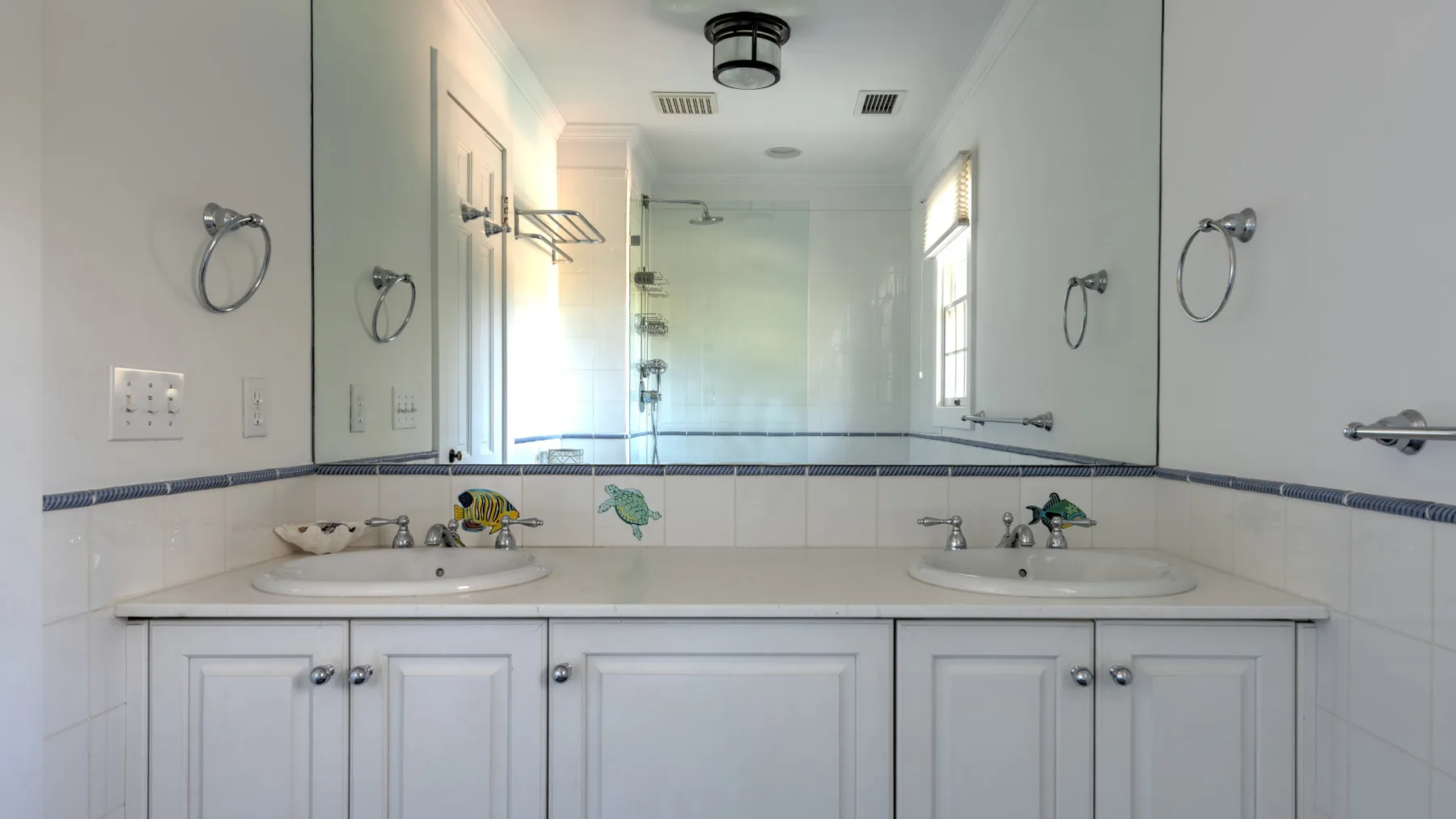 A bathroom vanity with two sinks sits beneath a large wall mirror.