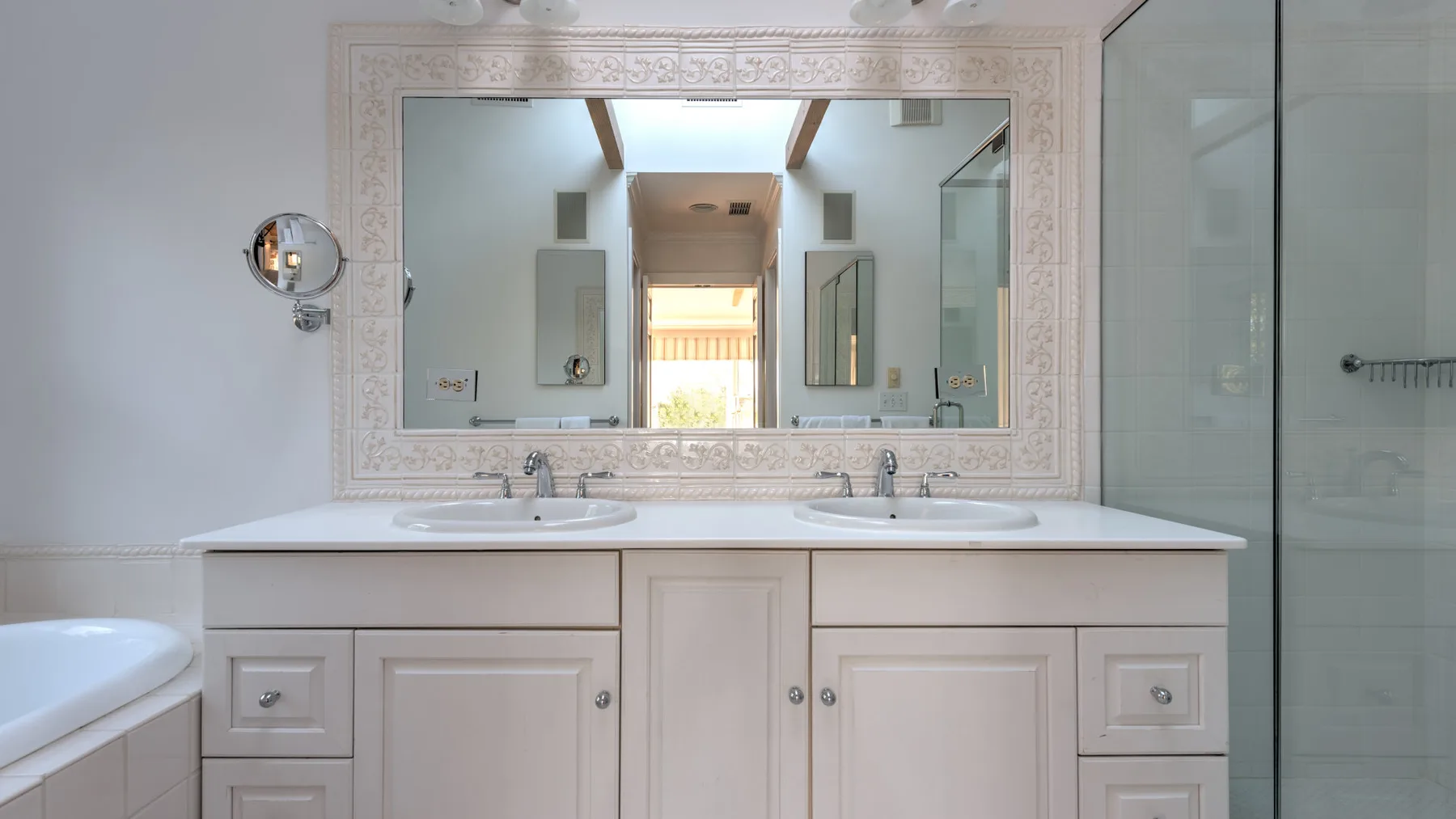 A bathroom vanity with a large mirror and a glass shower enclosure.