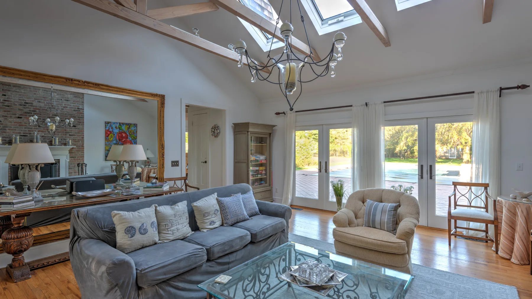 A bright living room with seating, a glass coffee table, and large windows.