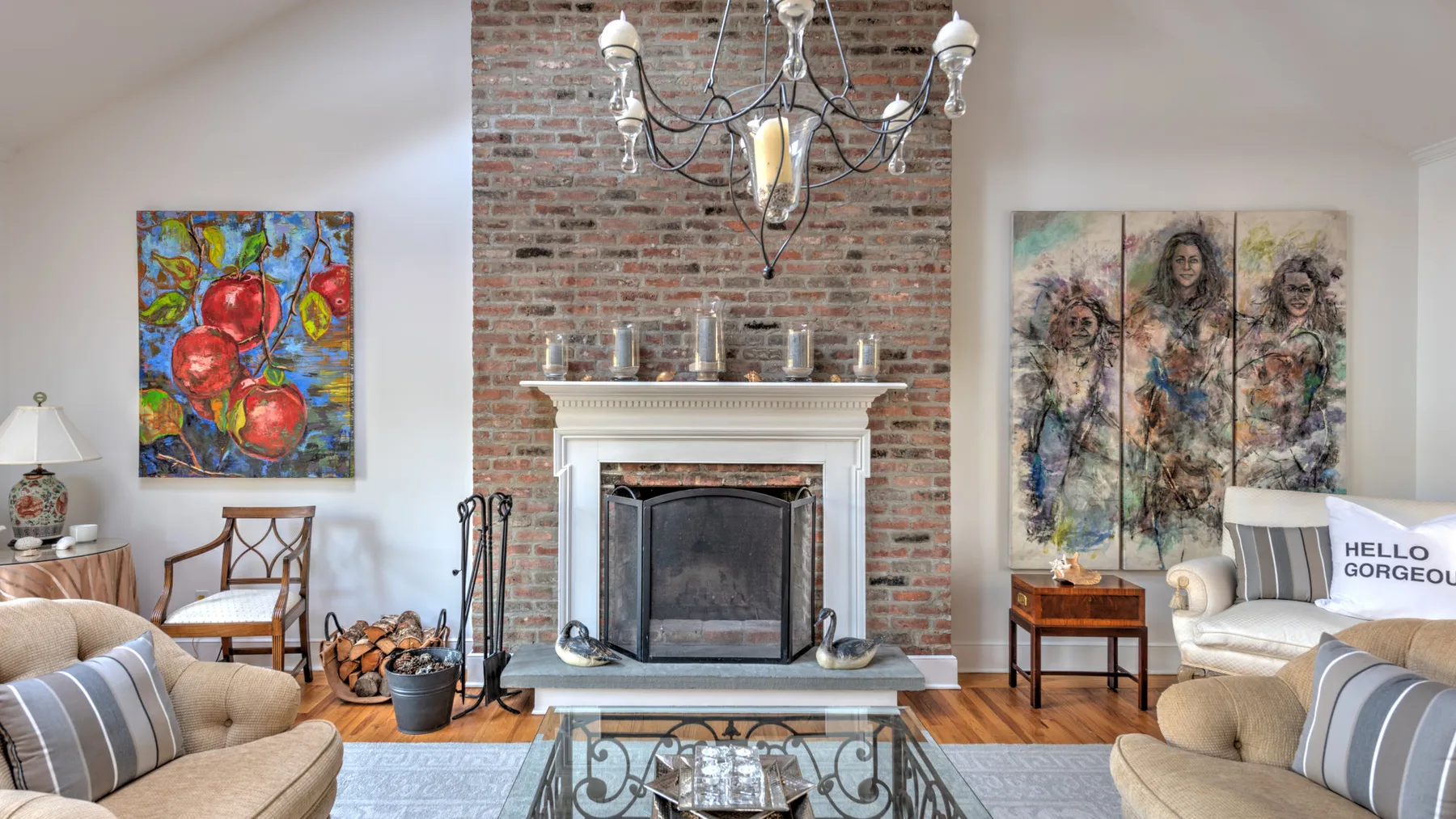 A living room with a brick fireplace, seating, and colorful artwork.