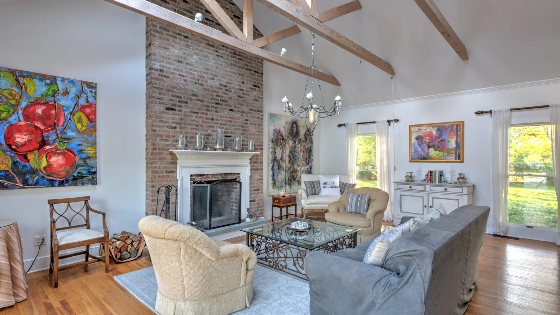 A bright living room with exposed ceiling beams and a brick fireplace.