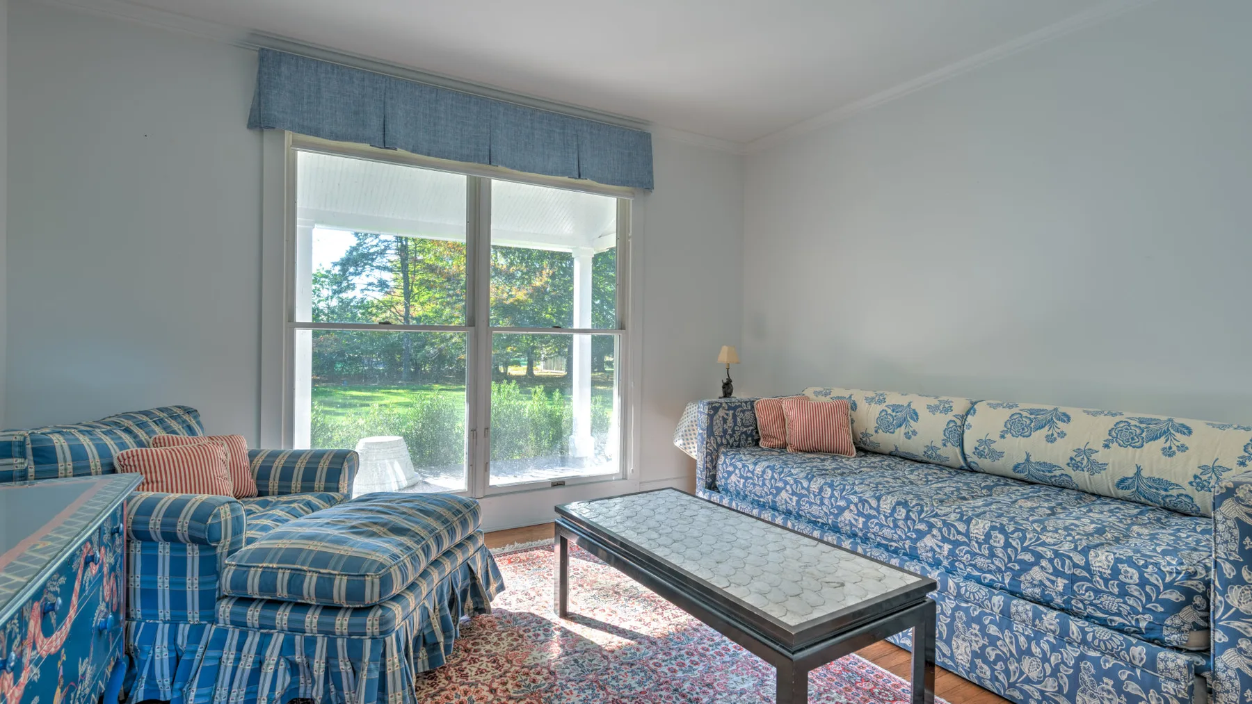 A living room with patterned seating, a coffee table, and a bright window.
