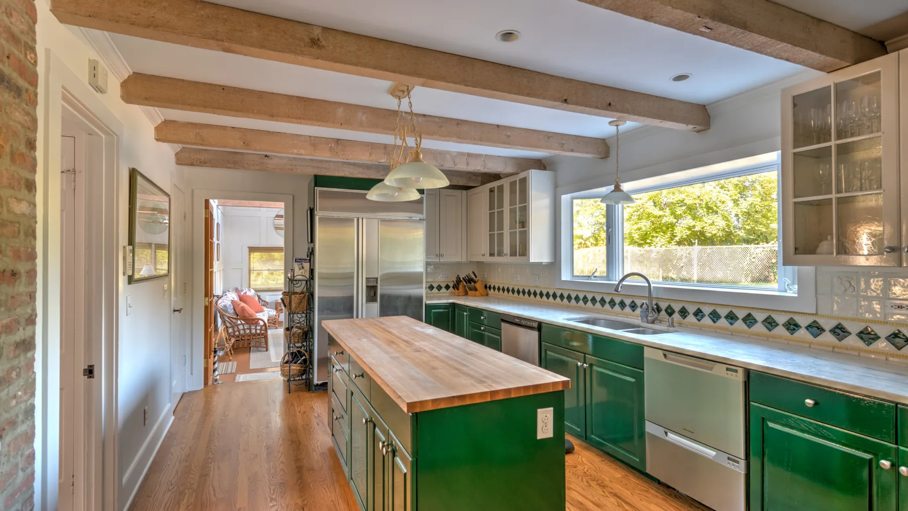 A bright kitchen with green cabinetry, a central island, and large windows.