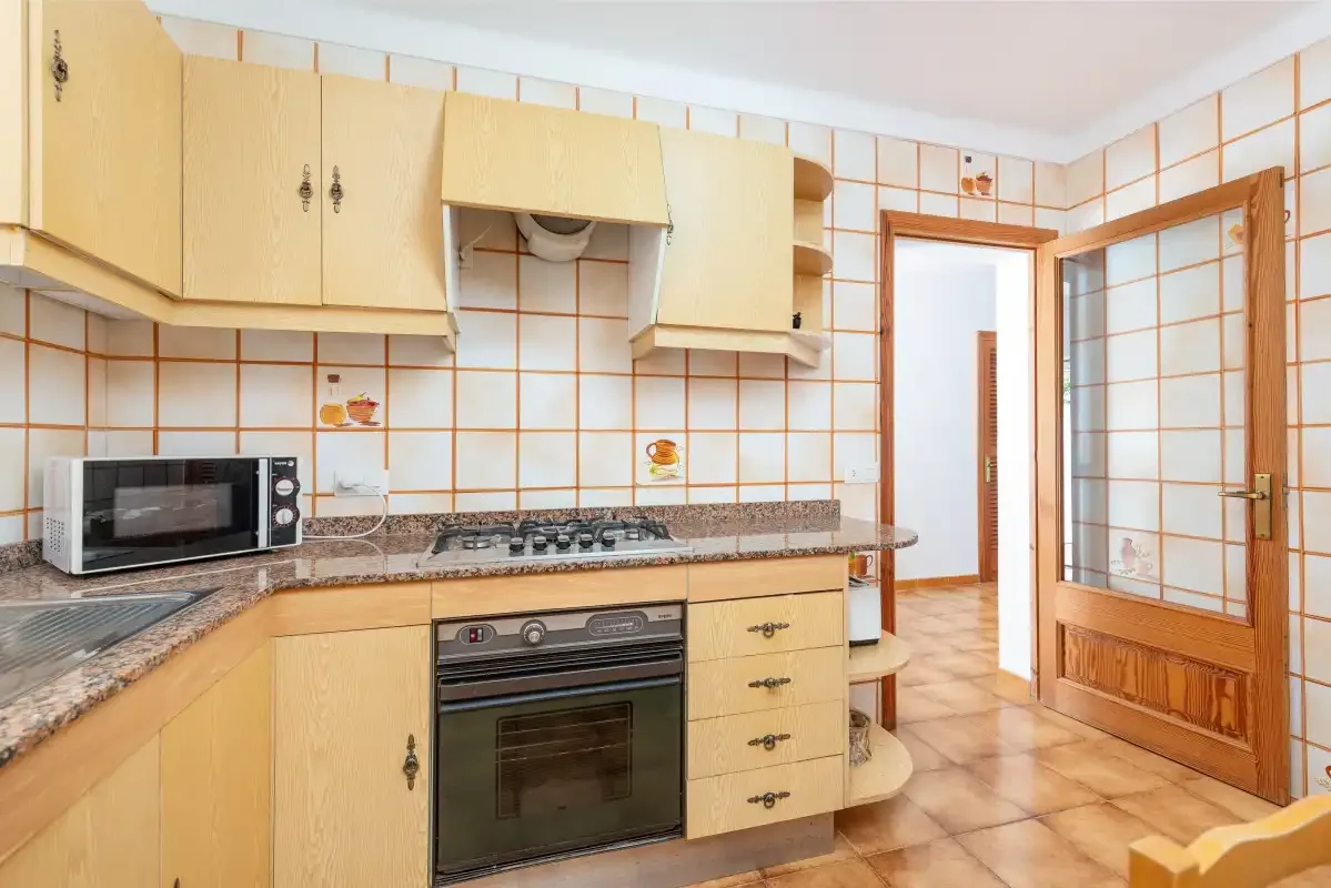 Una cocina con gabinetes de madera clara, una estufa y un horno.