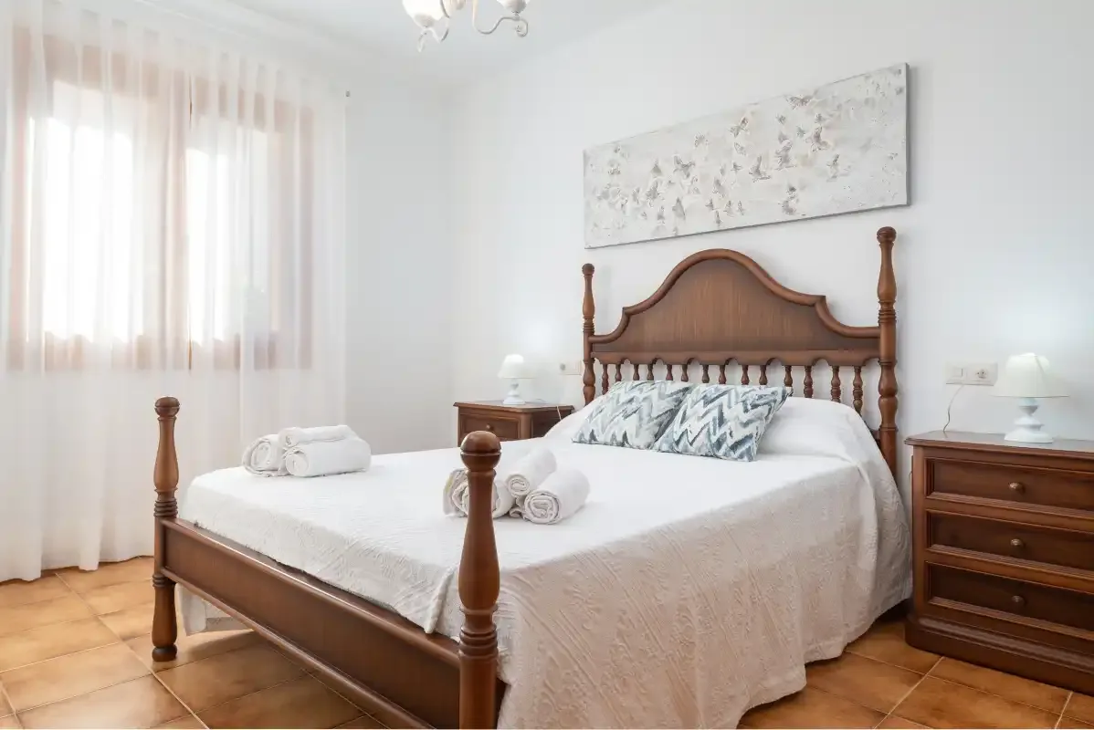 Un dormitorio luminoso con una cama de madera y mesitas de noche.