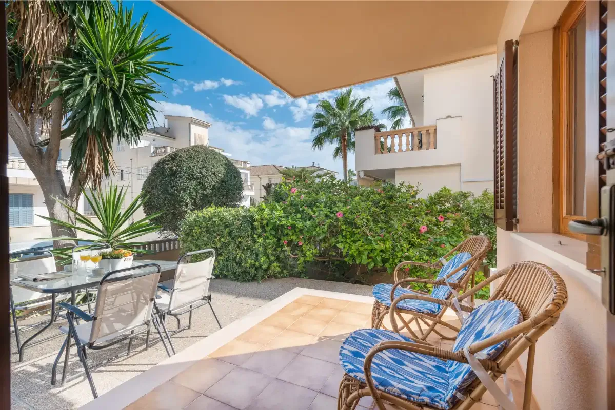 Un patio a la sombra con asientos al aire libre da a un jardín frondoso.