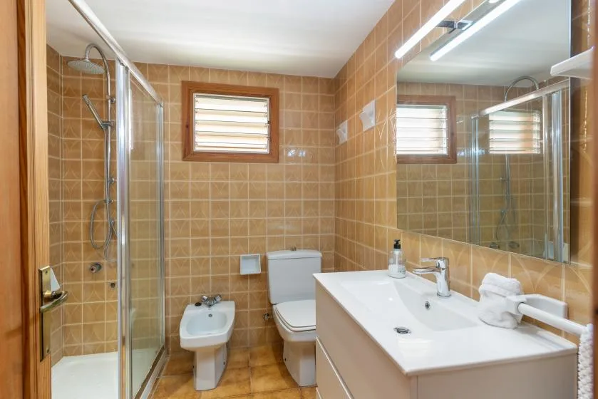 Un baño con azulejos, ducha de vidrio, inodoro y lavabo.