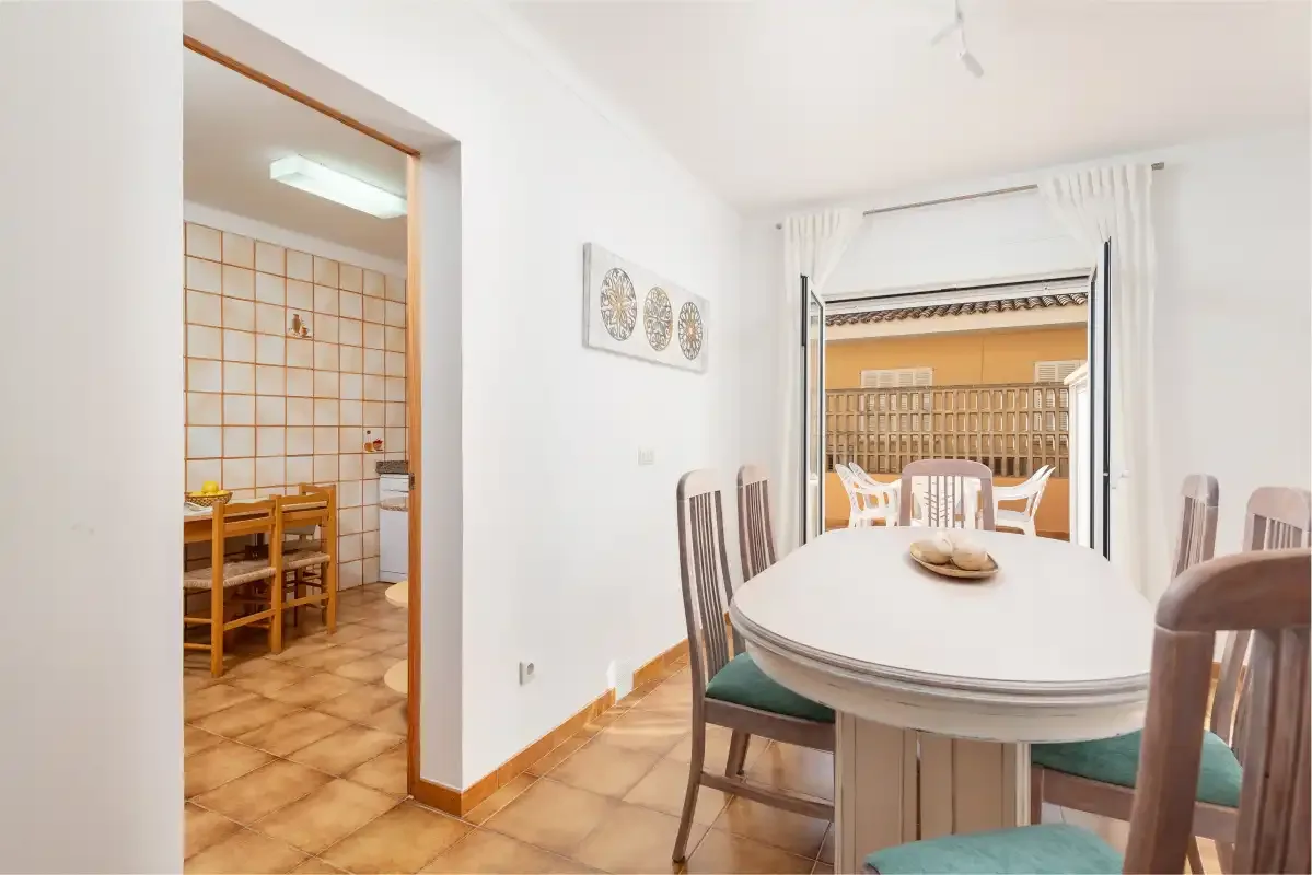 Comedor con una mesa ovalada y sillas junto a una puerta abierta.