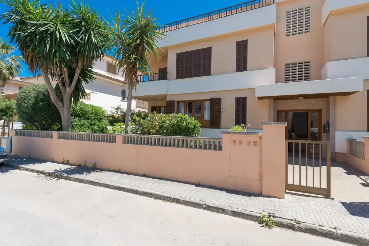 Edificio residencial con una entrada con reja y árboles en la parte delantera.