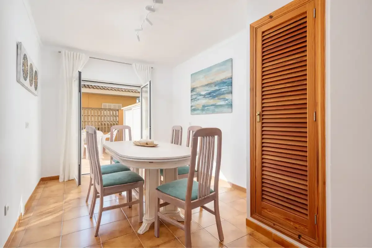 Comedor con una mesa y sillas junto a una puerta de madera con lamas.