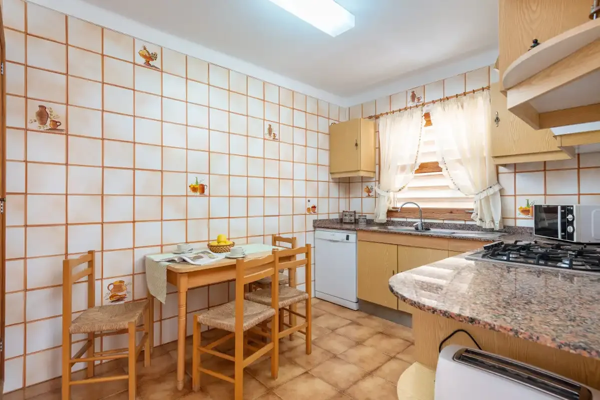 Una cocina alicatada con zona de comedor y una mesa junto a la encimera.