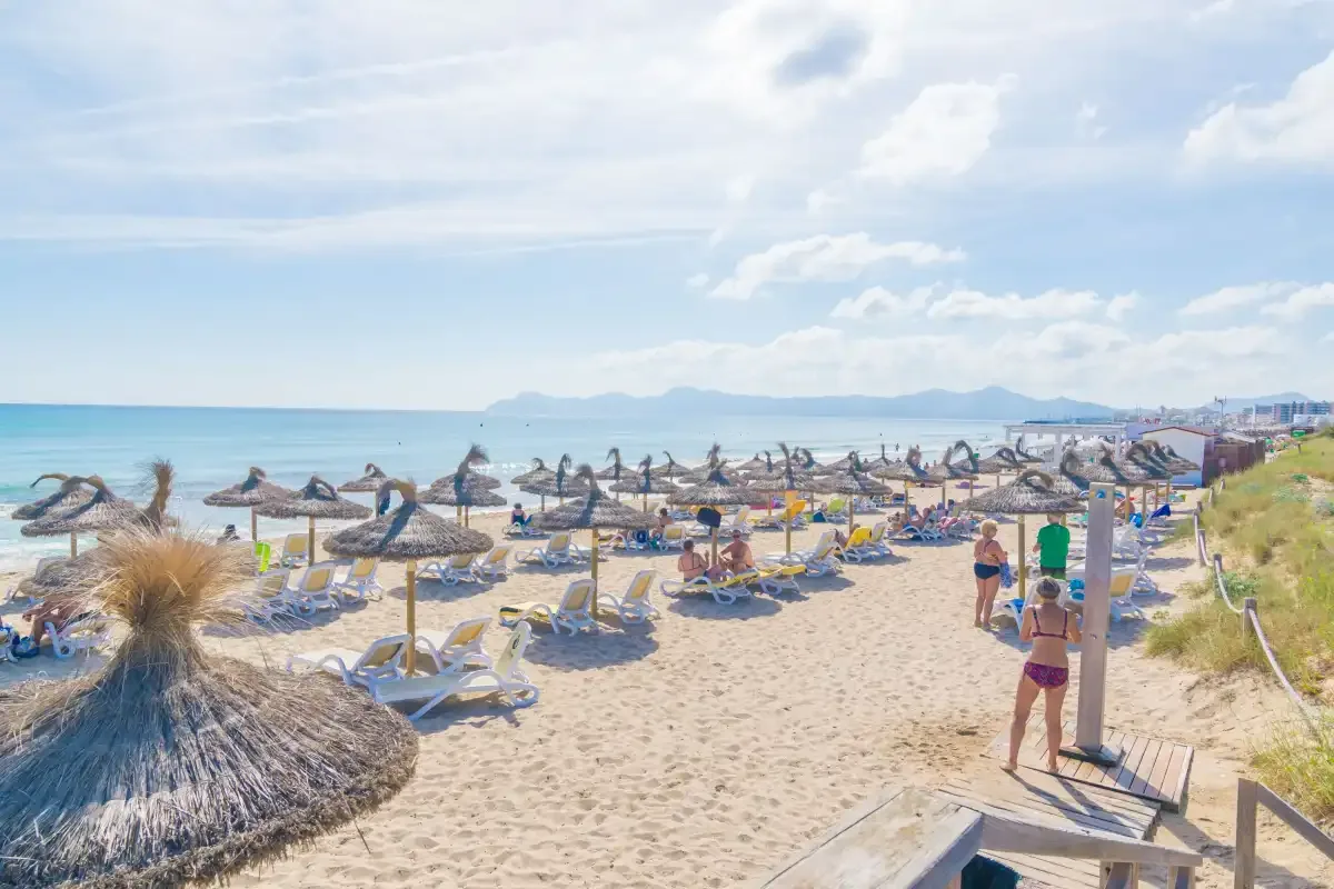 Una playa de arena con tumbonas y sombrillas junto al mar.