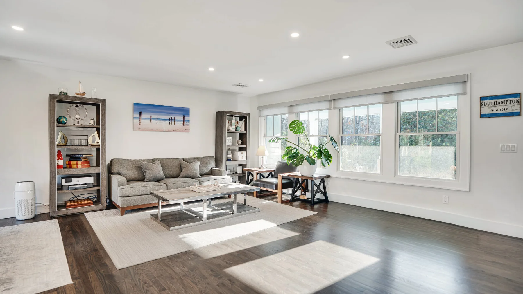 A bright living room with seating, a coffee table, and large windows.