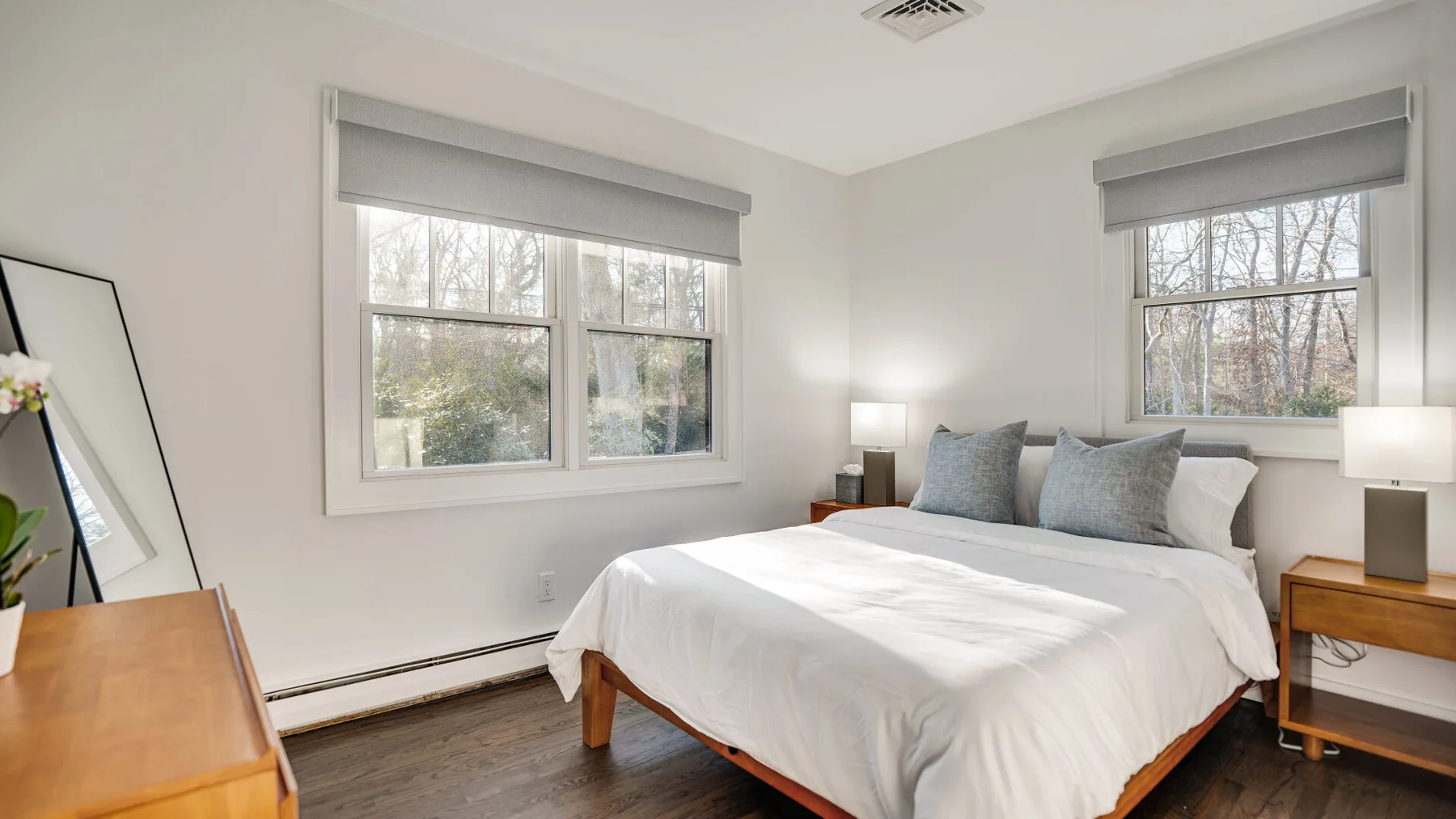 A bright bedroom with a bed between two windows.