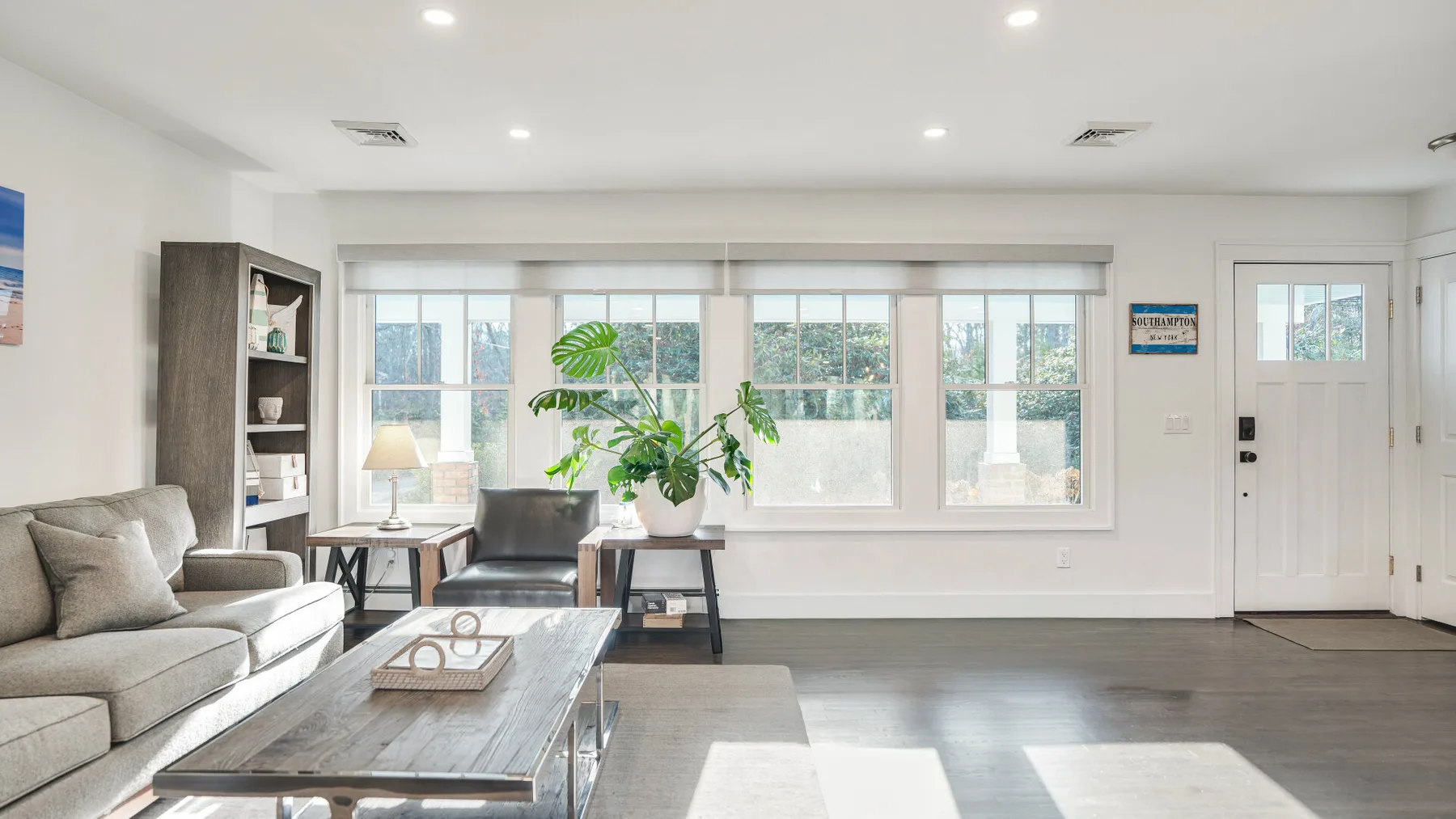 A bright living room with seating, a coffee table, and large windows.