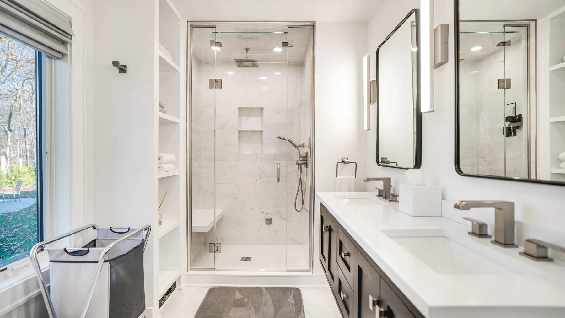 A bright bathroom with a glass shower and a long vanity.