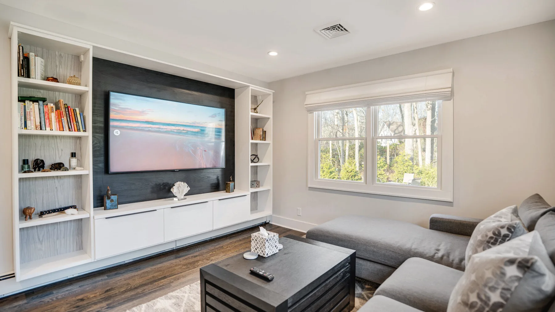 A living room with a television above a low cabinet and a sectional seating area.