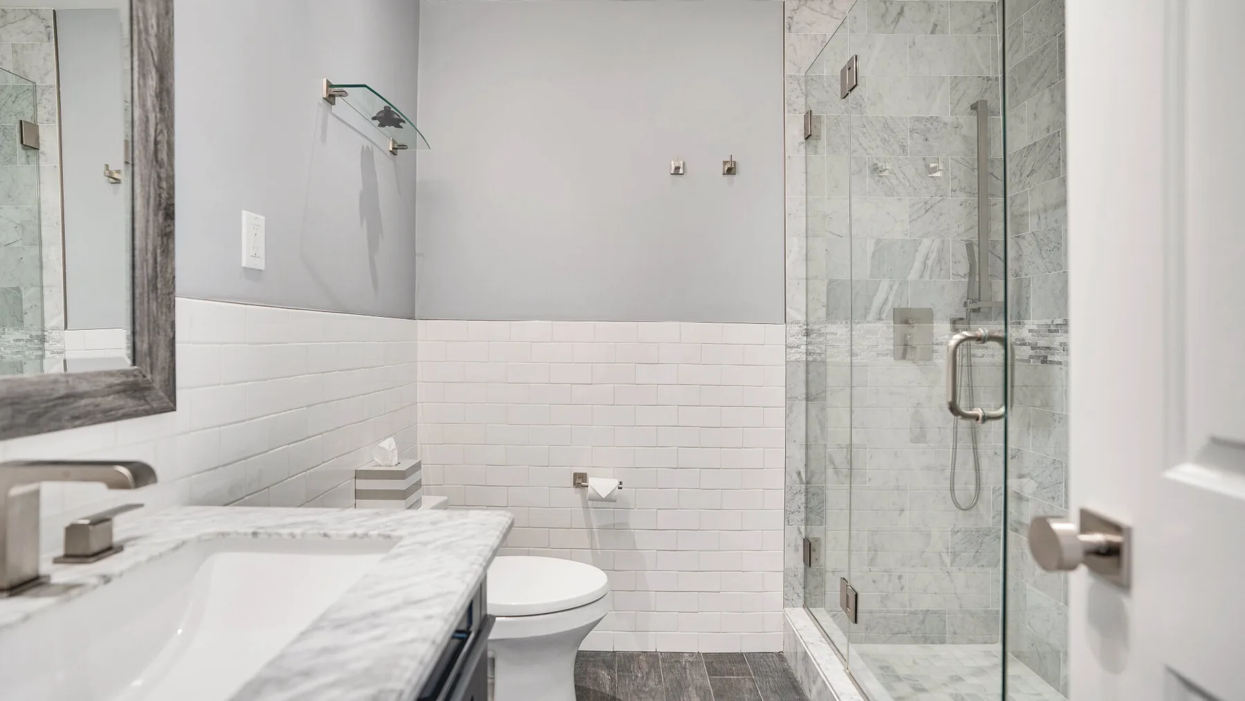 A bright bathroom with a sink and glass-enclosed shower.