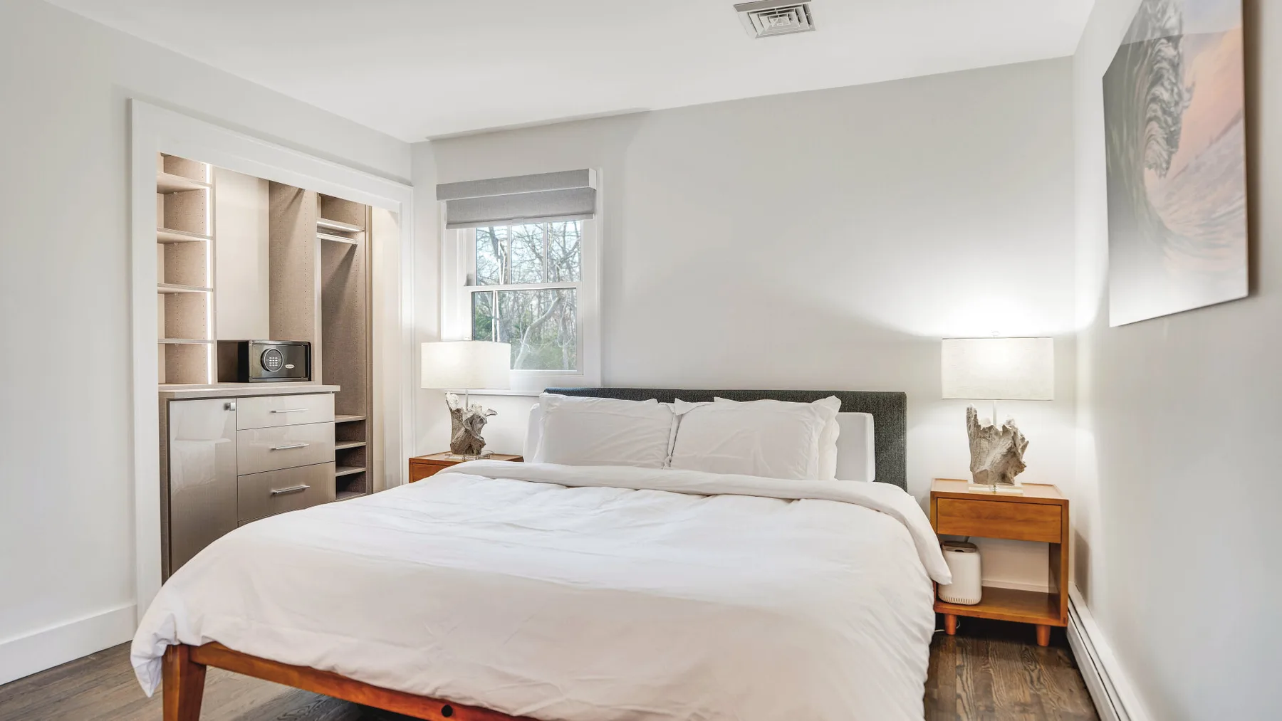 A bedroom with a neatly made bed, bedside tables, and a window.
