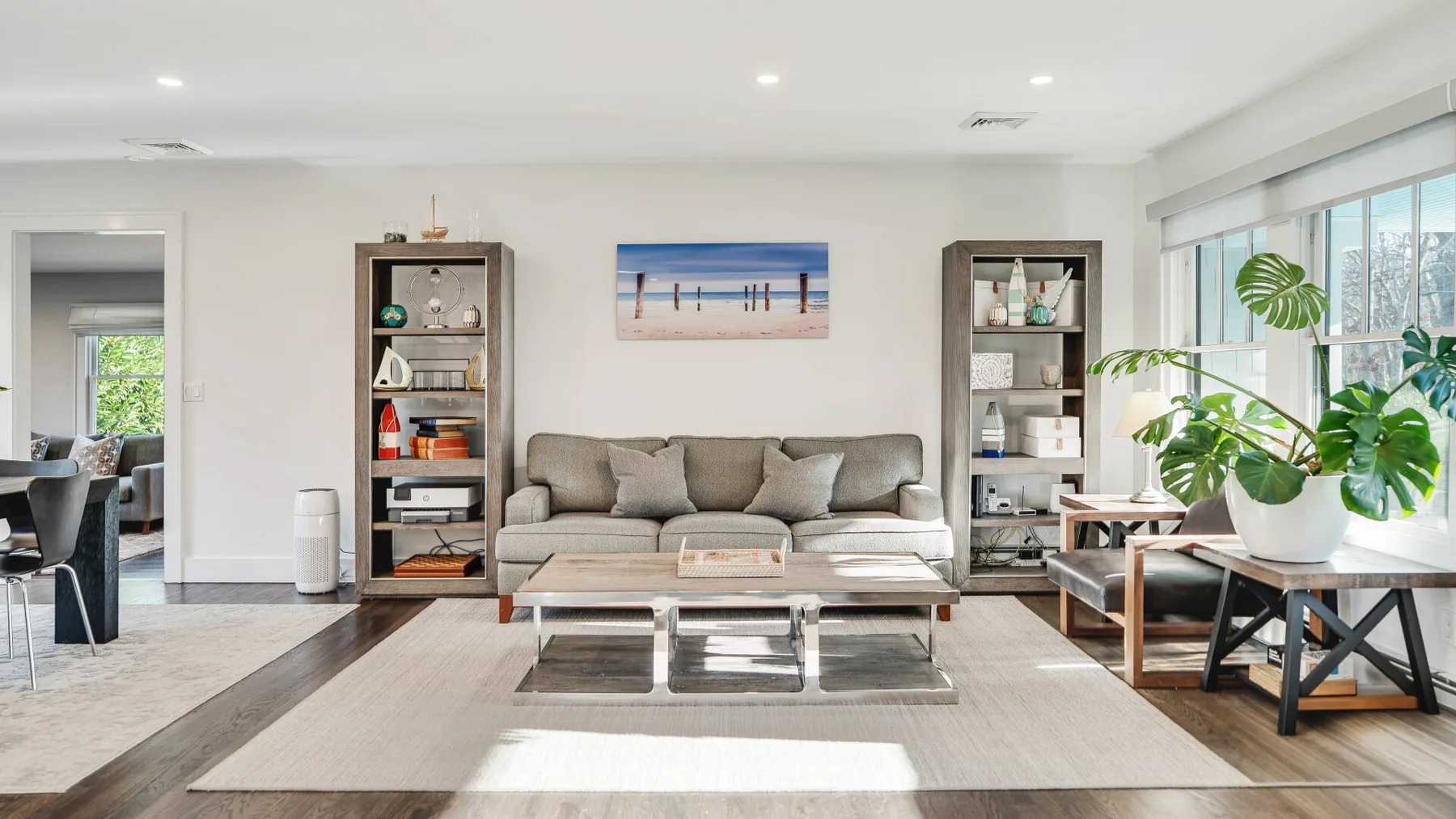 A bright living room with seating, a coffee table, and large windows.