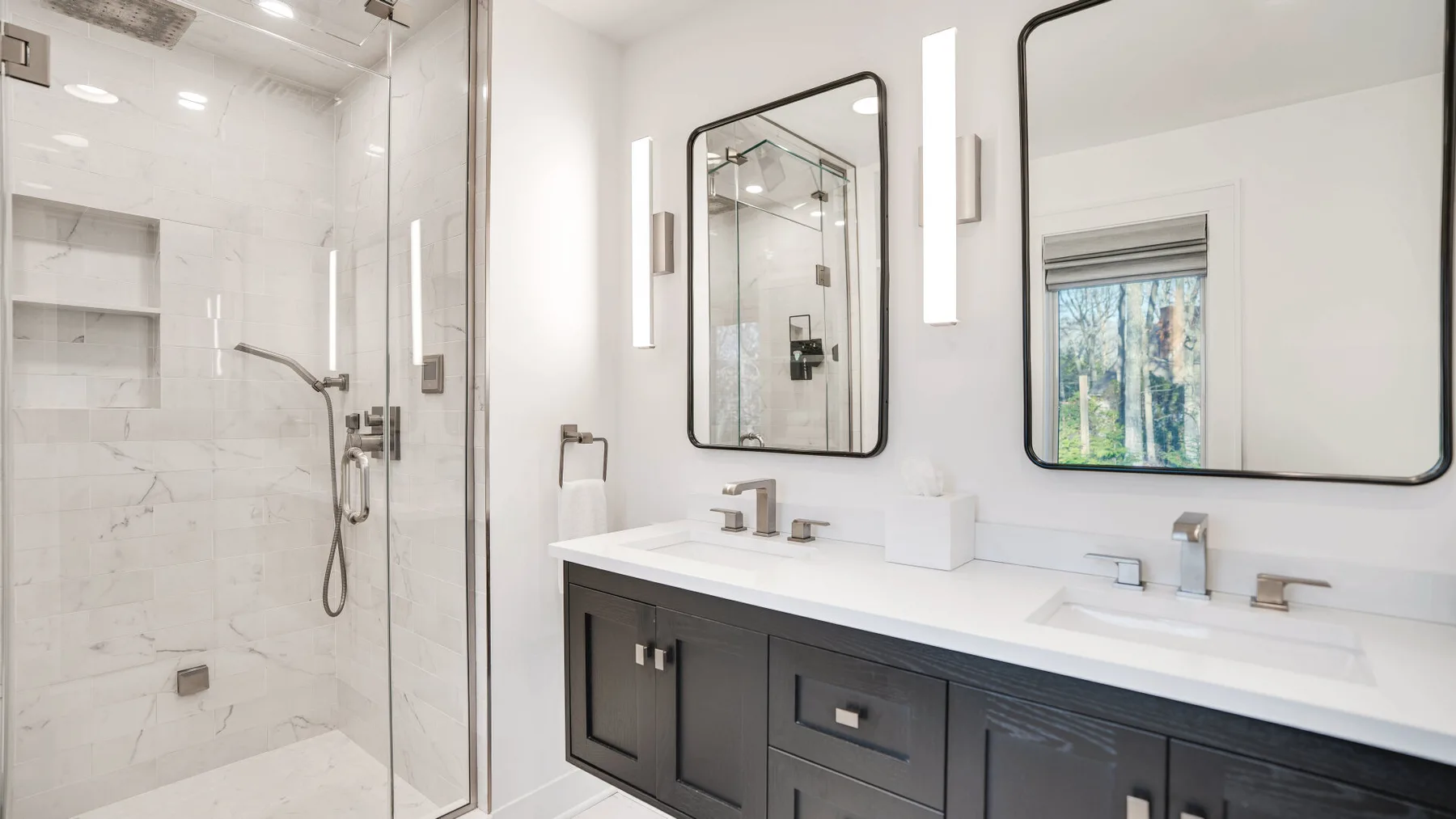 A bright bathroom with a long vanity and glass-enclosed shower.