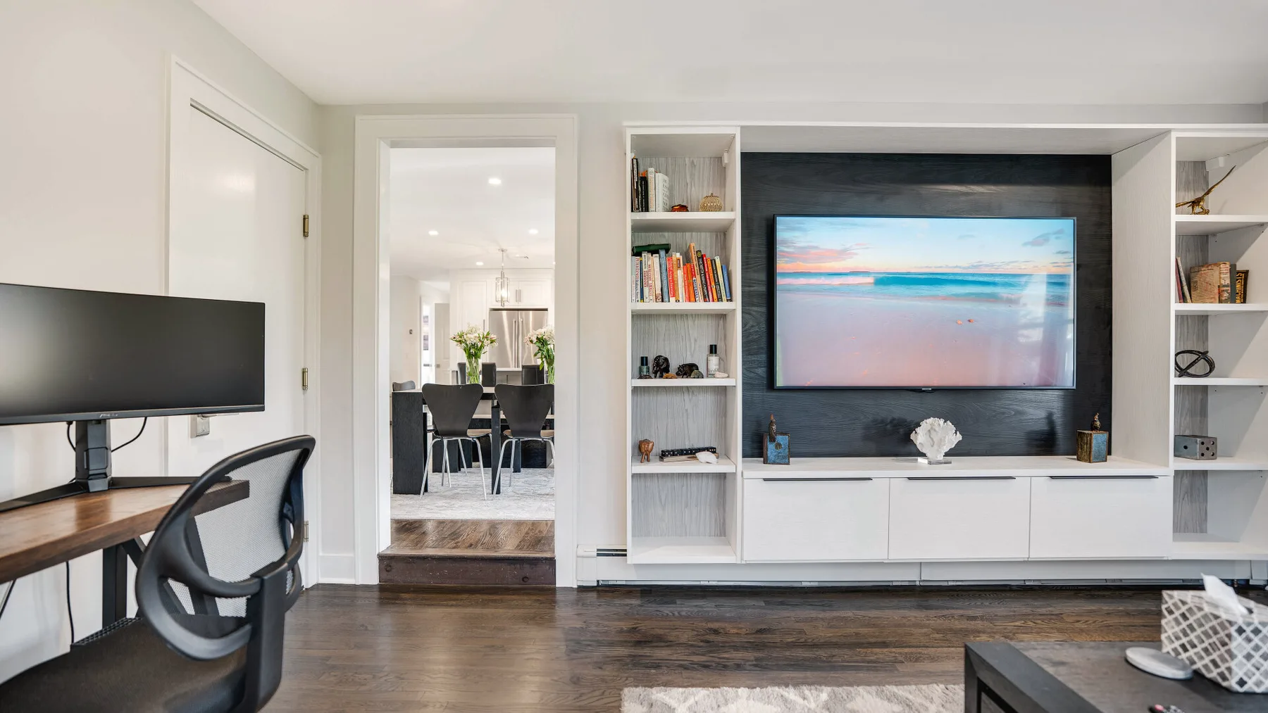 A modern living room with a wall-mounted television and built-in shelving.
