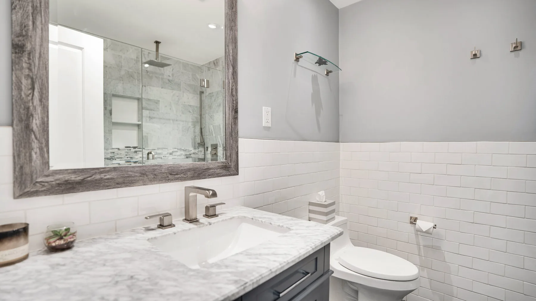 A bathroom with a marble vanity, wall mirror, and toilet.