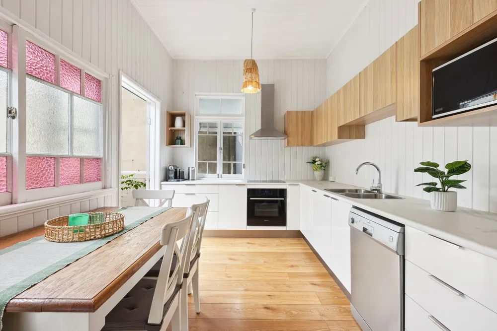 Cocina luminosa con una mesa de comedor junto a las ventanas.