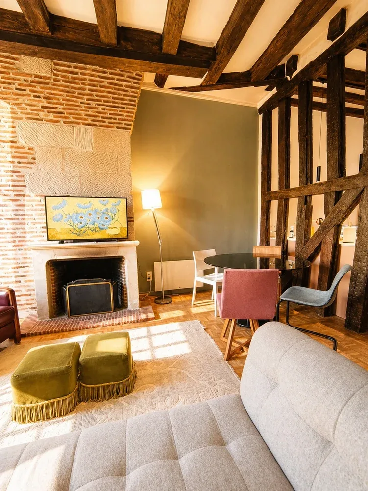 Una sala de estar con chimenea, asientos y vigas de madera a la vista.