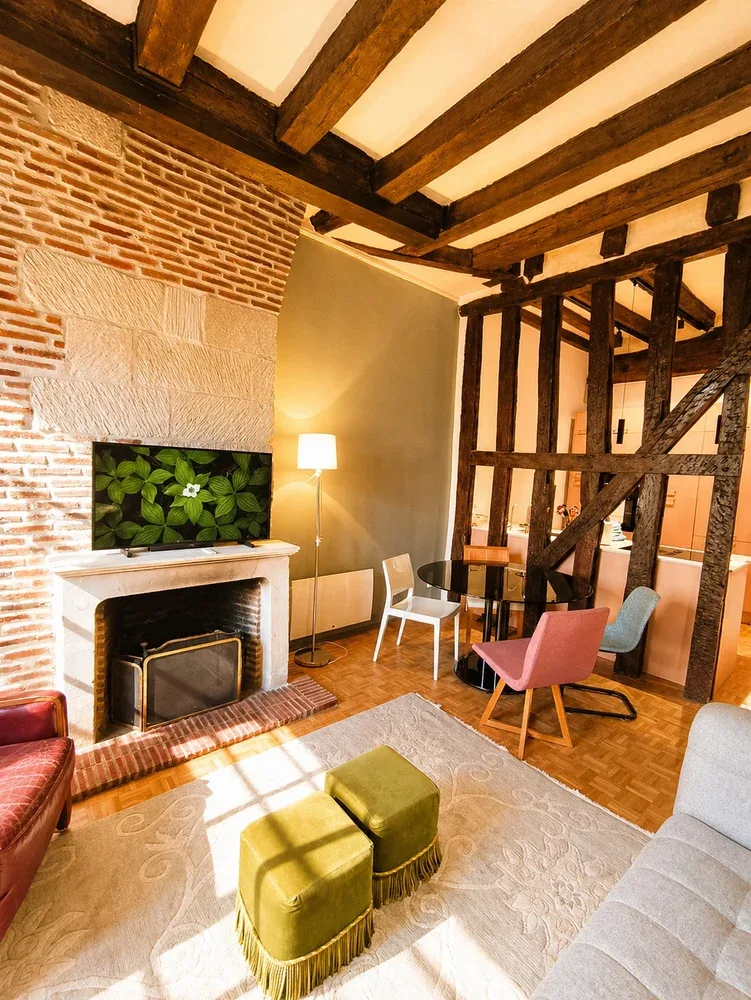 Una sala de estar con vigas de madera expuestas, paredes de ladrillo y asientos junto a una chimenea.