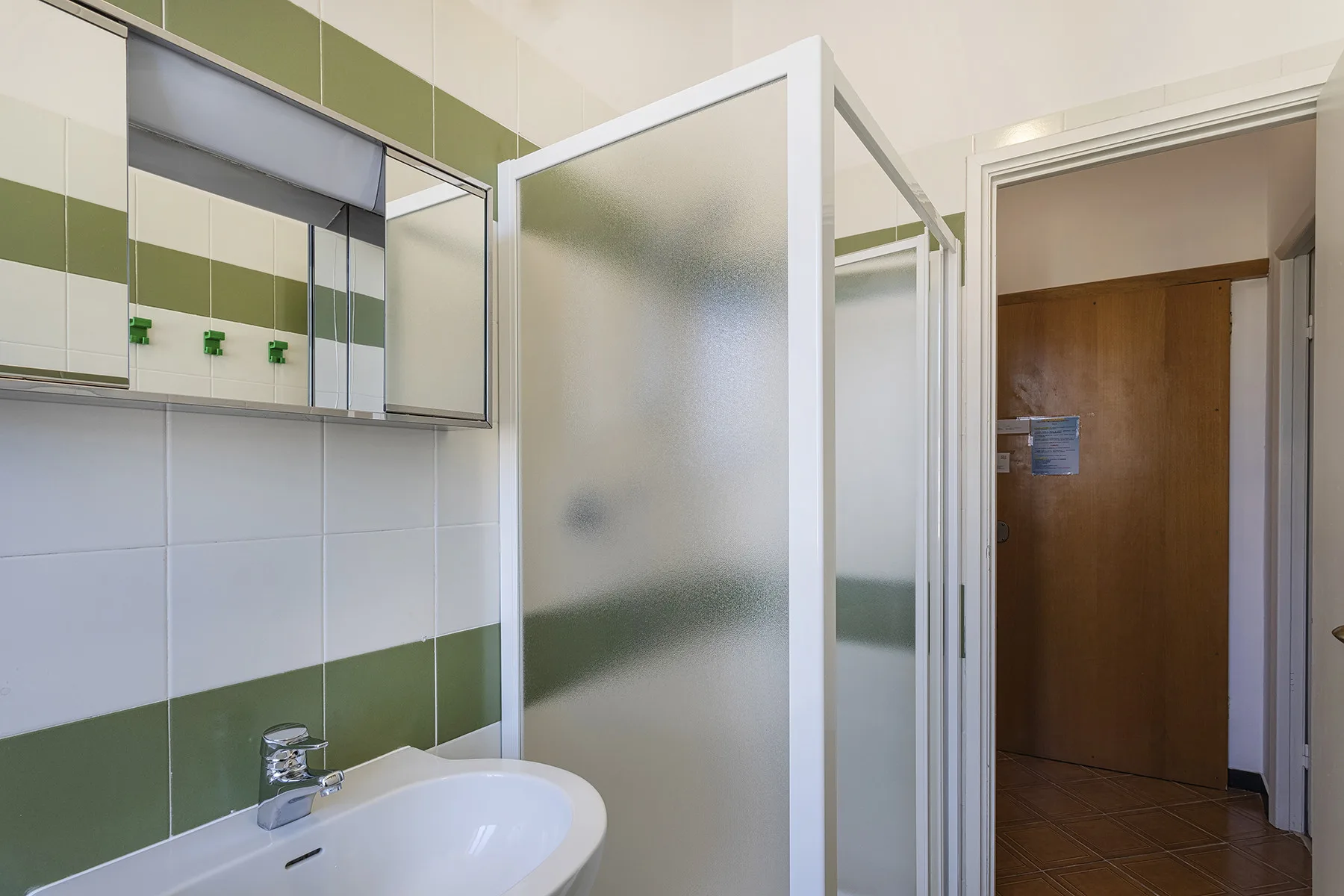 Un baño con lavabo y una mampara de ducha de vidrio esmerilado.